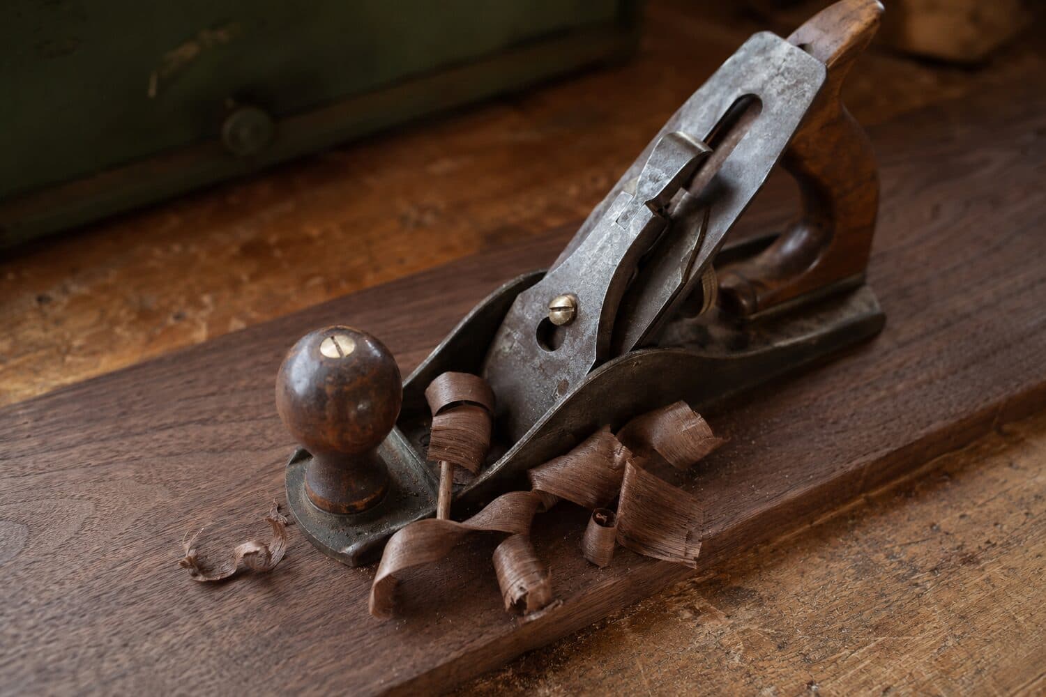 Hand plane peeling a curl of shavings off a board on a workbench